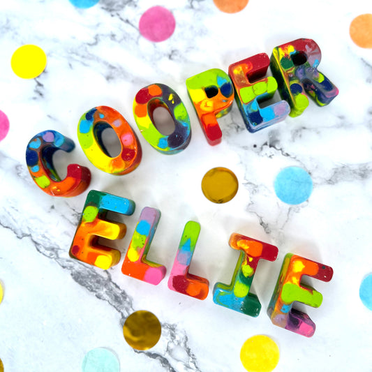 Colorful letter-shaped objects spelling 'COOPER' and 'ELLI' on a marble background with colorful dots.